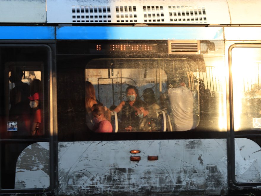 Passengers visible through a city bus window in warm light